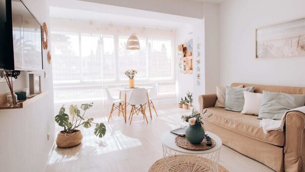 Una sala luminosa con sofá, mesa de centro y comedor.