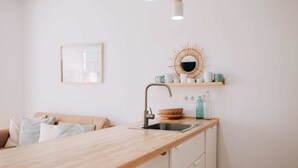 Una cocina moderna con encimera de madera, un lavabo y un espejo decorativo.