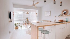 Una cocina moderna con una isla central, armarios blancos e iluminación colgante.