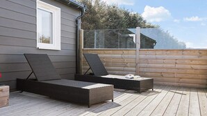 Una terraza con dos sillas reclinables y piso de madera.
