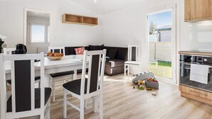 Una cocina moderna con armarios blancos, horno integrado y comedor con sillas y mesa blancos.