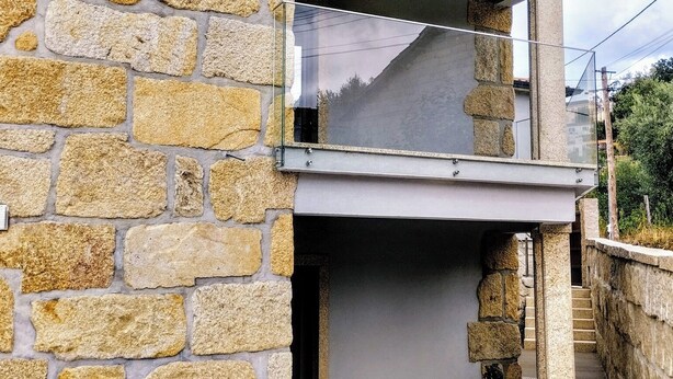 A stone building with a modern design, featuring a large glass window and a staircase leading to an upper level. - R3 Service Casa do Pomar (Vouzela)