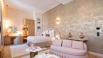 A modern bedroom with two beds, a sofa, a vanity, and a large window.