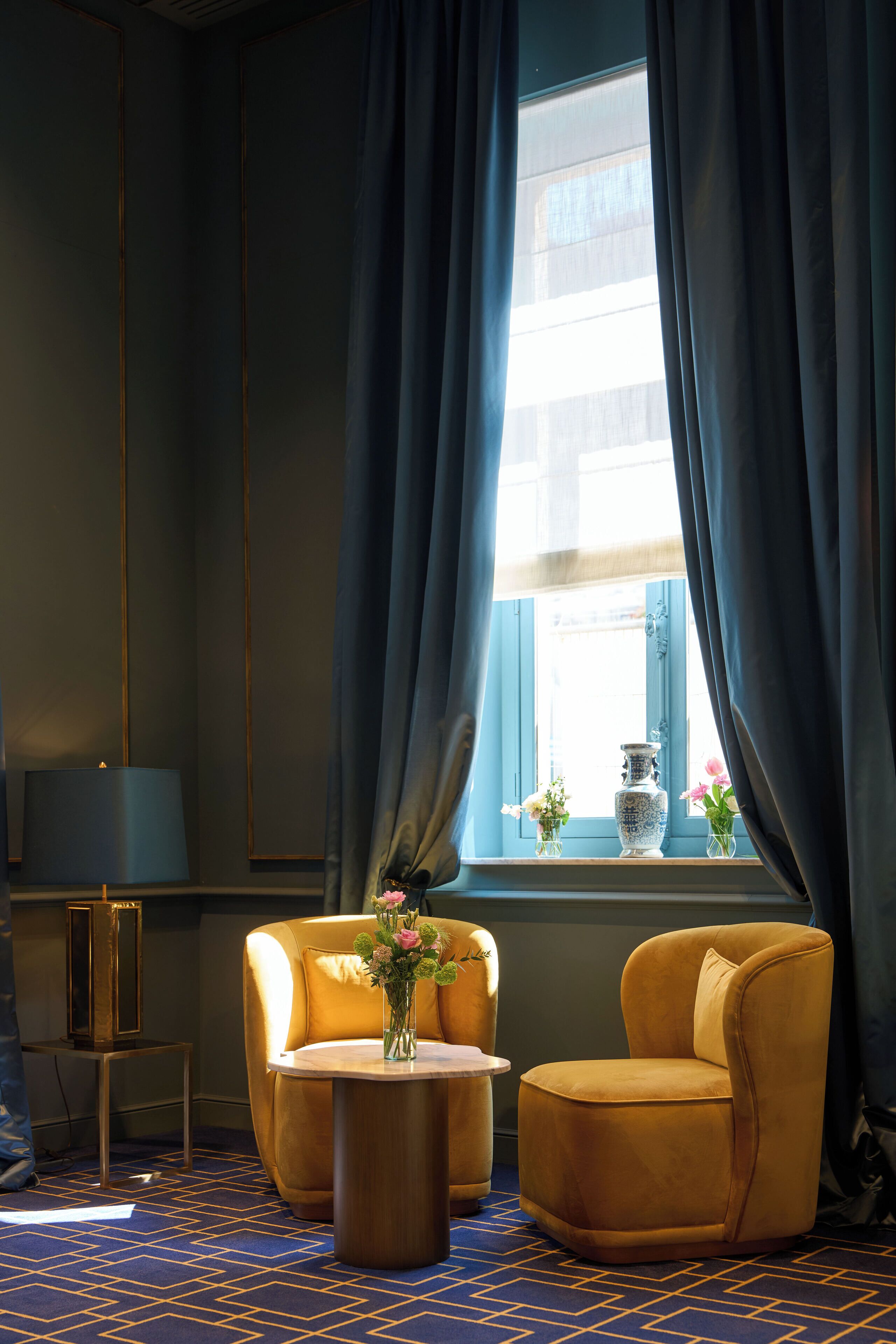 Una habitación con un ventanal grande, dos sillones, una mesita y una lámpara.