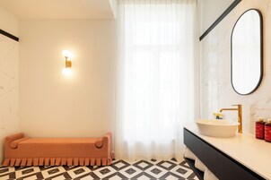 Un bagno moderno con una vasca, un lavabo con rubinetto dorato e uno specchio.