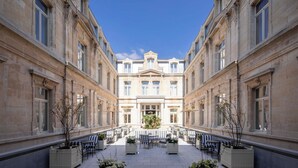 A courtyard with a central fountain, surrounded by seating areas and potted plants. - Les Bains De Spa (Spa)