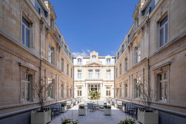 A courtyard with a central fountain, surrounded by seating areas and potted plants. - Les Bains De Spa (Spa)
