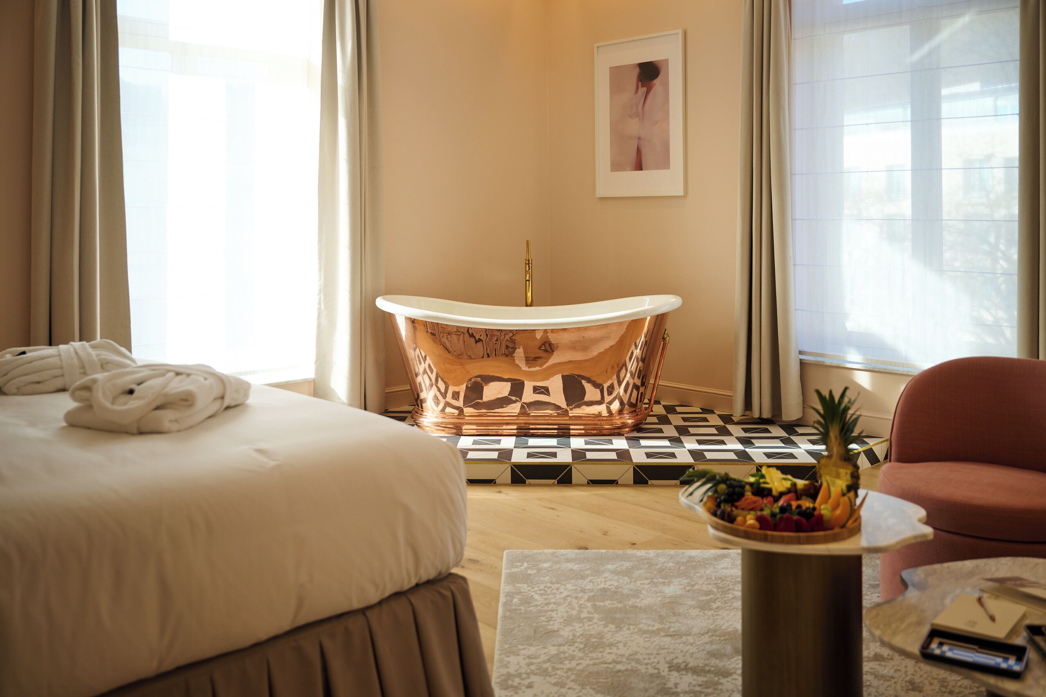 Habitación de hotel con una cama grande, una bañera, un frutero y una silla.