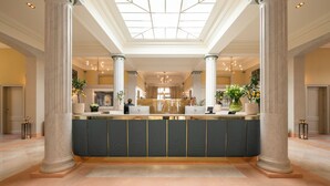 A reception area with marble columns, a central counter, and a skylight. - Les Bains De Spa (Spa)