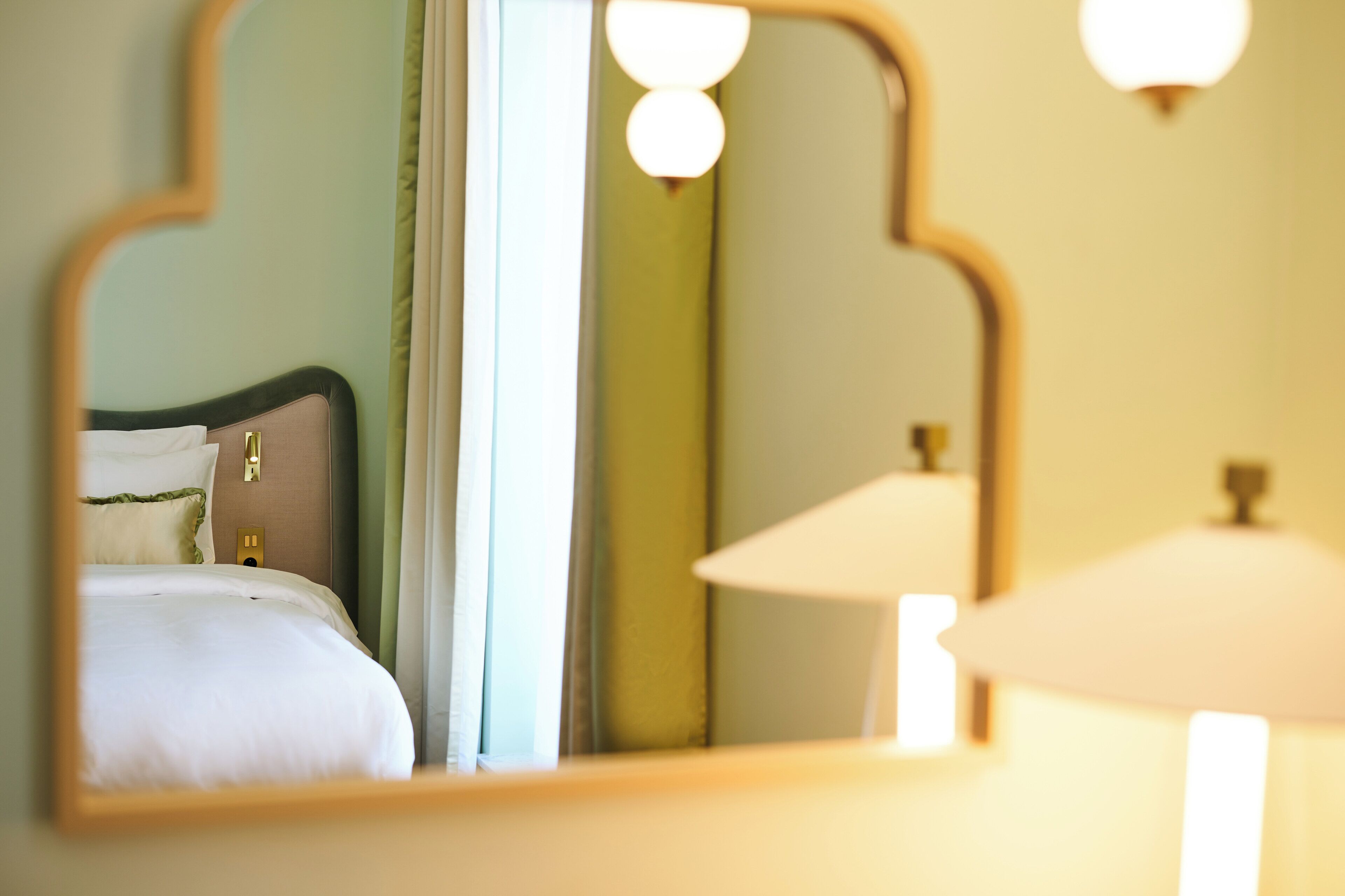 A bedroom with a bed, a mirror, and a lamp.
