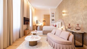 A modern living room with a sofa, a coffee table, and a TV. There is a wooden cabinet and a lamp on a side table. - Les Bains De Spa (Spa)