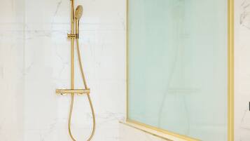 A modern bathroom with a gold showerhead and a glass partition.