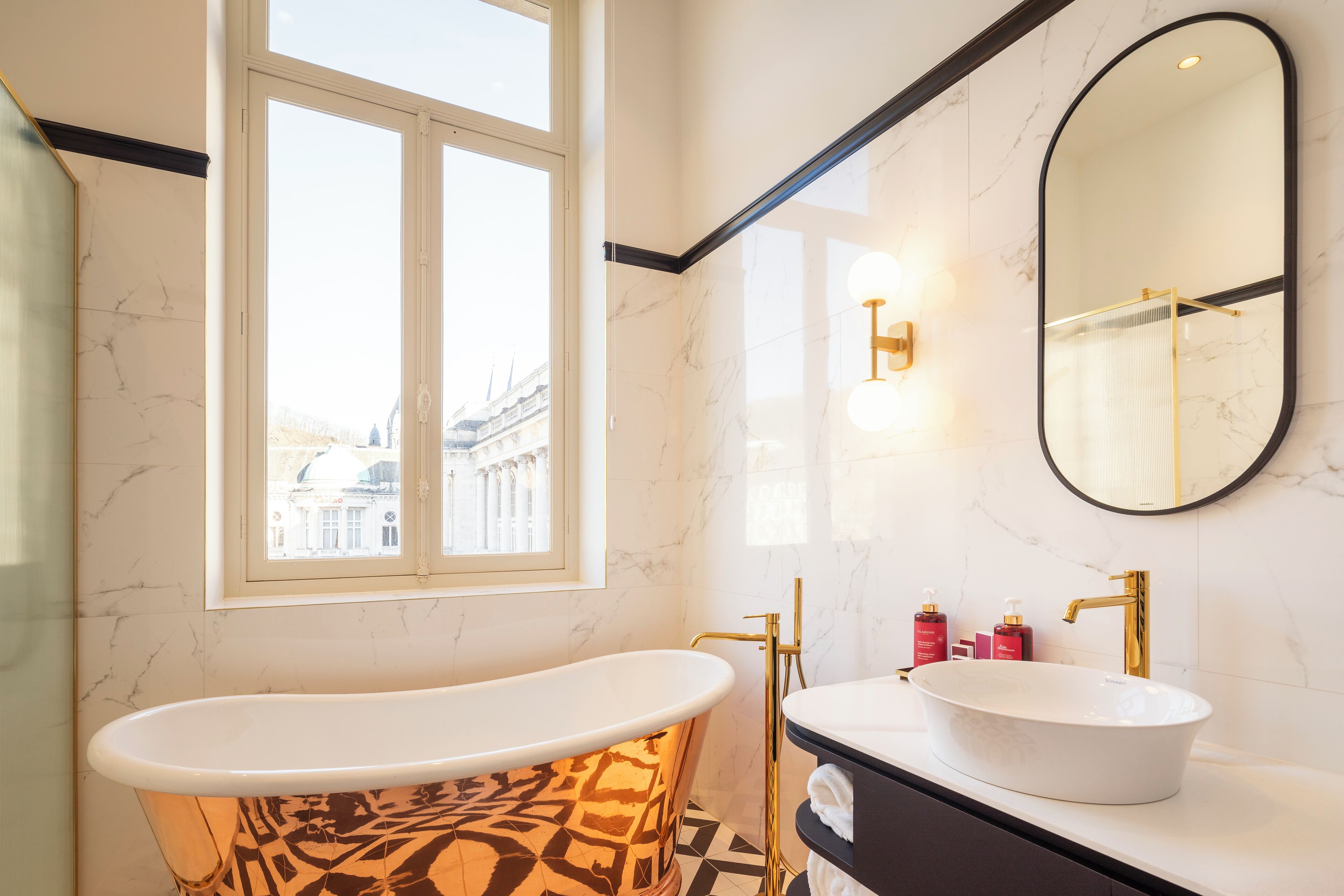 A bathroom with a freestanding bathtub, a vanity with a sink, and a large mirror.