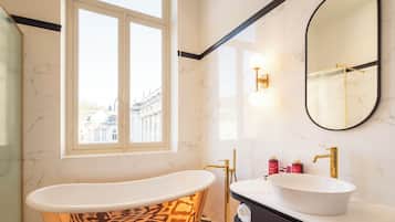Une salle de bain avec une baignoire sur pieds, un meuble-lavabo et un grand miroir.