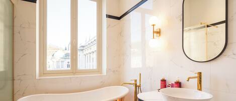 A bathroom with a freestanding bathtub, a vanity with a sink, and a large mirror.