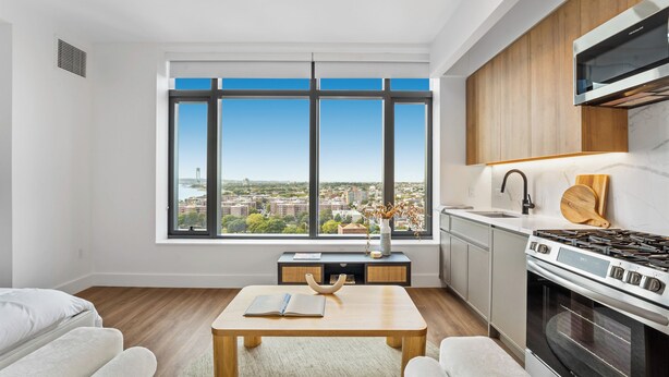 A modern kitchen with a large window, a built-in stove, and a view of the city.