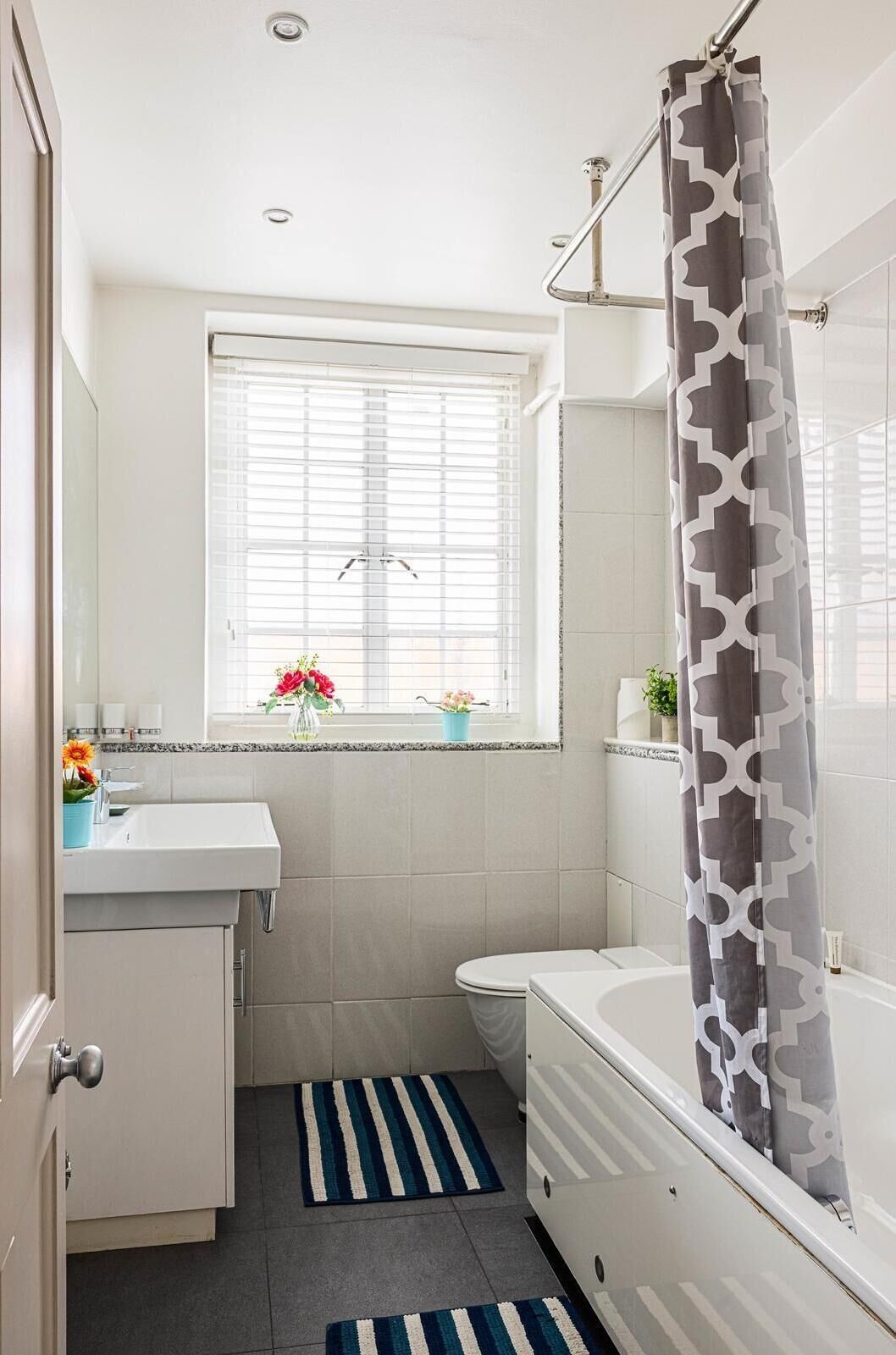 Une salle de bain moderne avec un lavabo blanc, des toilettes, une baignoire et un rideau de douche.