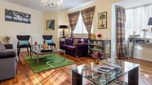 Ein modernes Wohnzimmer mit einem violetten Sofa, einem Glastisch und einer Kronleuchter.