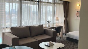 Une chambre d’hôtel avec un canapé, une table basse ronde, un bureau et un lit.