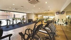 Une salle de sport équipée de tapis de course, de vélos d’appartement et d’appareils de musculation.