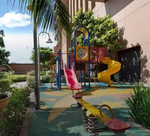 Ein Spielplatz mit Rutsche, Klettergerüsten und einer Wippe.
