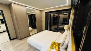 Une chambre d’hôtel moderne avec un grand lit, une table de chevet avec une lampe, un miroir et une vue sur la ville par la fenêtre.