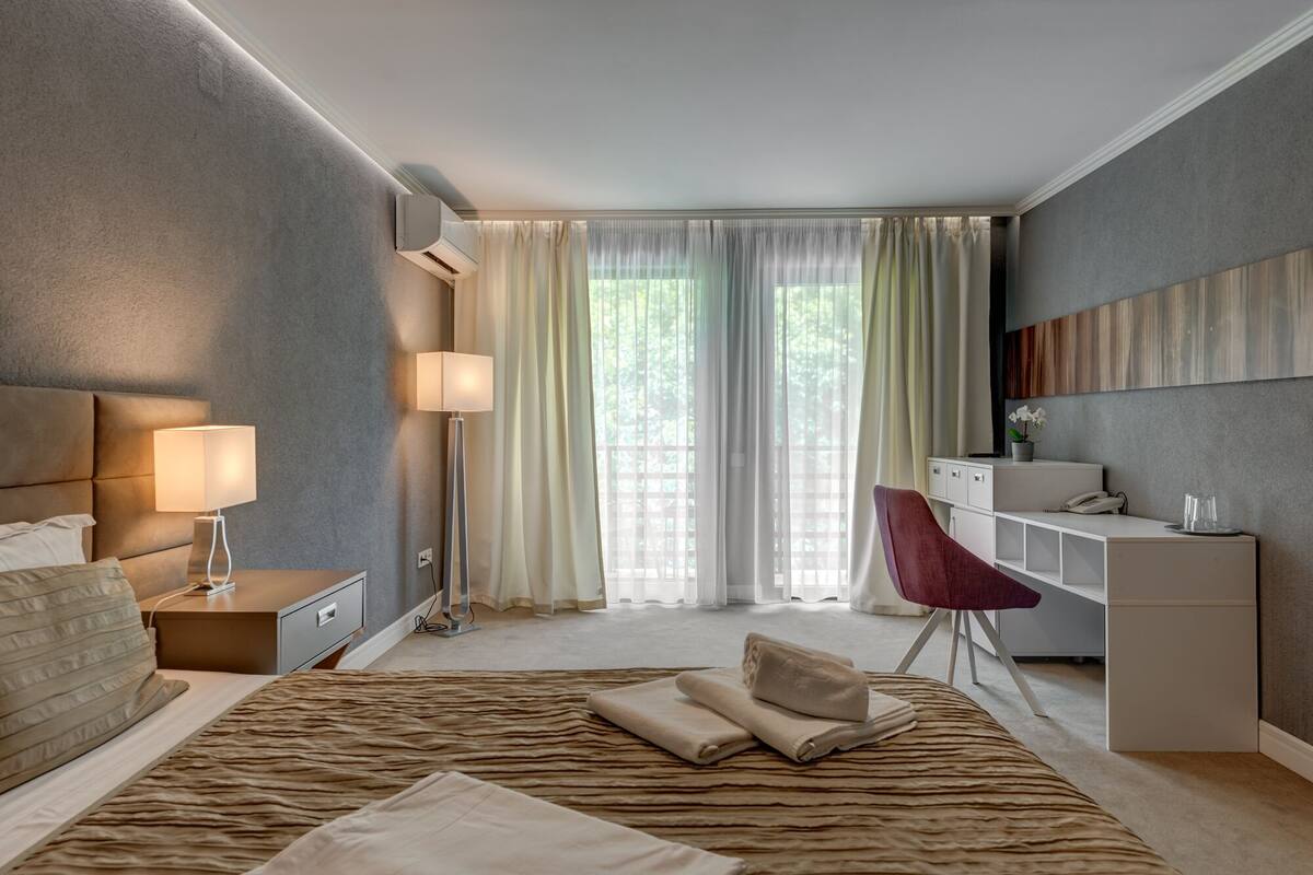 Une chambre d’hôtel moderne avec un grand lit, des lampes de chevet, un bureau et une chaise.
