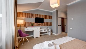 Een hotelkamer met een bed, een bureau, een stoel, een televisie en een kledingkast.