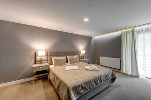 A modern bedroom with a large bed, bedside lamps, a nightstand, and a window with curtains. - Hotel Roberto Slanic Prahova (Slanic)