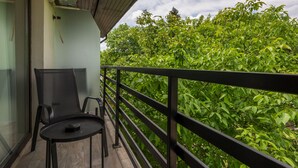 Een balkon met een zwart metalen hekwerk, een zwarte stoel en een klein rond tafeltje.
