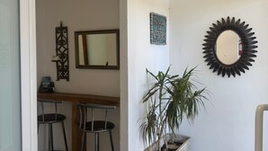 Ein kleines Büro mit Schreibtisch, zwei Stühlen, einer Topfpflanze, einem Spiegel und einem Wanddekor.