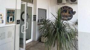 Ein Hotel Eingangsbereich mit Glastür, Blumentöpfen und einer Wandtafel.