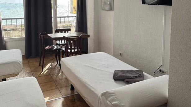 Ein Zimmer mit einem Bett, einem Schreibtisch und einem Stuhl. Ein Fernseher ist an der Wand angebracht.