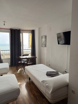 A room with a bed, a desk, and a chair. There is a TV mounted on the wall. - Habitaciones la Mar (Altea)