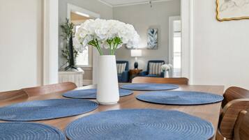 A dining table with blue placemats and a white vase with white flowers.