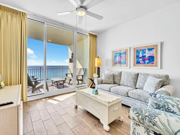 Ein Balkon mit Blick auf das Meer, eine Couch, ein Couchtisch und zwei gerahmte Kunstwerke an der Wand.