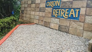 A stone wall with a sign reading "ORION RETREAT". - Orion Retreat (Darjeeling)