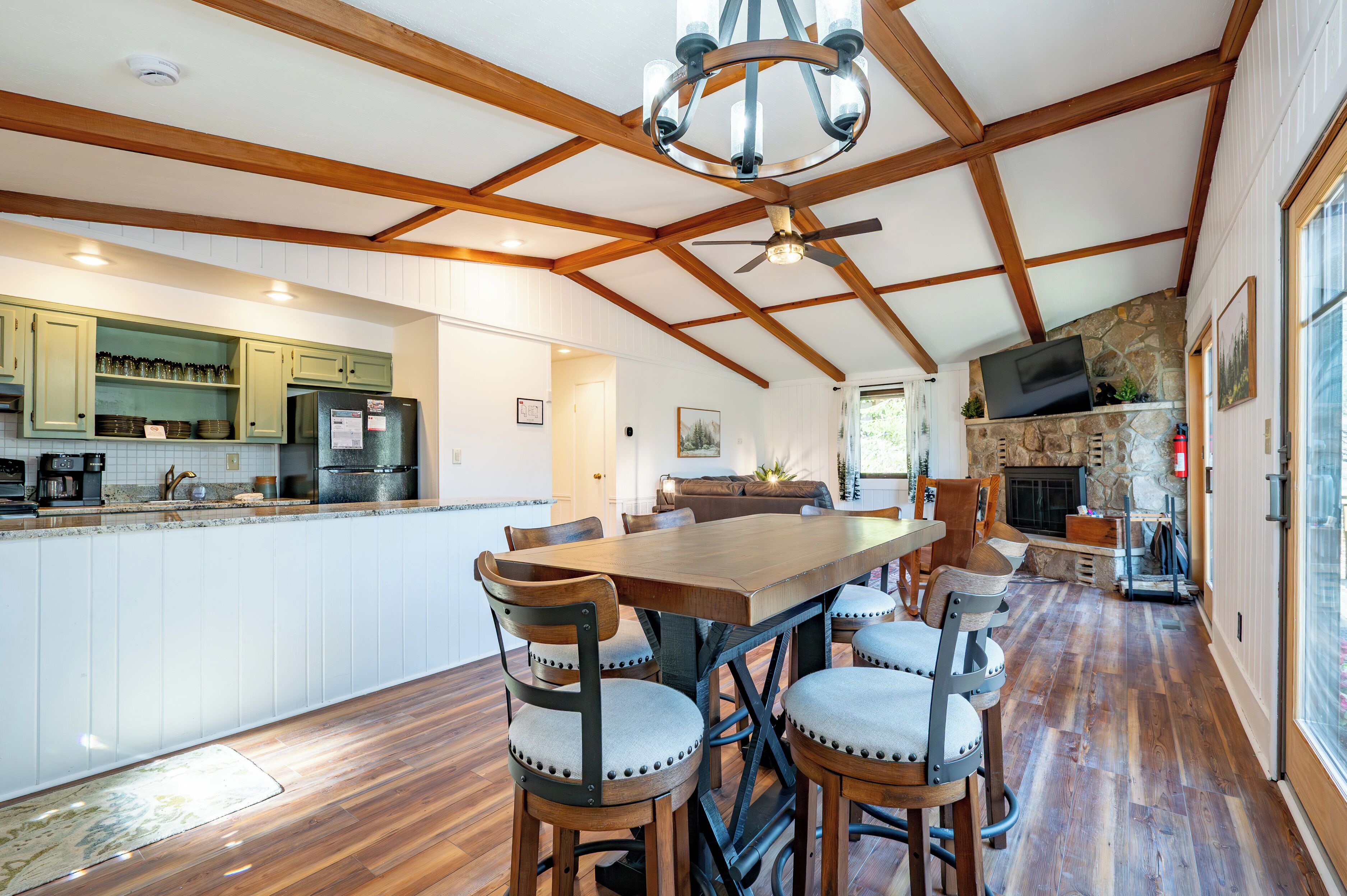 Una cocina amplia con vigas de madera, un comedor con una mesa grande y sillas, y una chimenea de piedra.