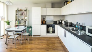 Eine moderne Küche mit weißen Schränken, einer schwarzen Arbeitsplatte und einem Essbereich mit Tisch und Stühlen.