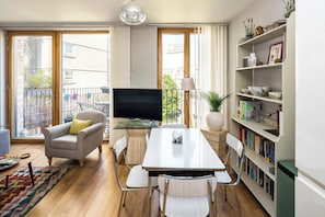 Een moderne woonkamer met een flatscreen televisie, een eettafel en een boekenkast.