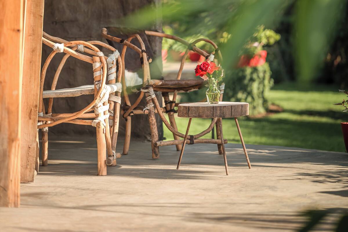 A rustic wooden hut with a thatched roof, a wooden table, and wicker chairs.