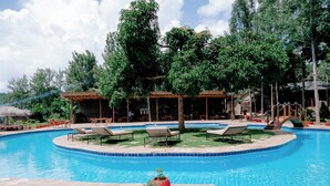 A swimming pool with lounge chairs and potted plants. - Mtoni river Lodge (Arusha)