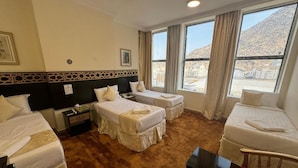 Habitación de hotel con dos camas individuales, un sofá, una mesita y vistas a un paisaje montañoso.