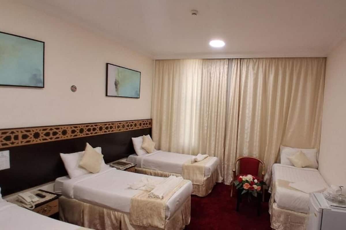 Ein Hotelzimmer mit zwei Einzelbetten, einem Schreibtisch, einem Sessel, einem Fernseher und einem roten Teppich.