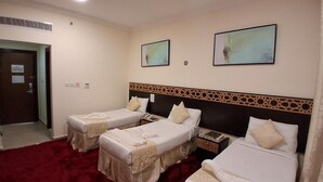 Una habitación de hotel con dos camas individuales, alfombra roja y un cabecero decorativo.