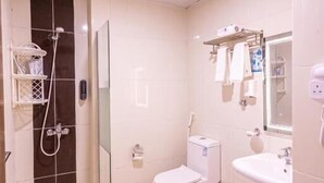 Un baño con ducha, inodoro, lavamanos y cabina de ducha con mampara de vidrio.