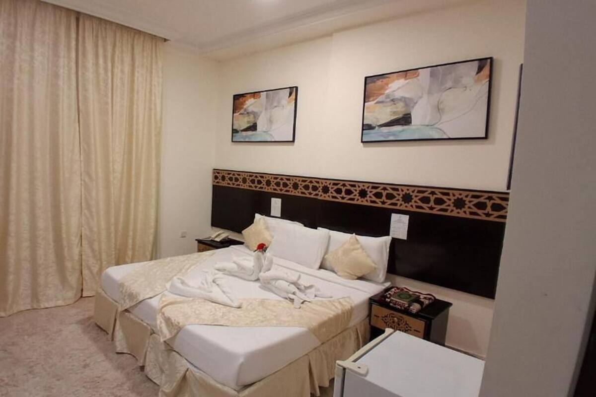 Ein Hotelzimmer mit einem großen Bett, zwei Nachttischen und einem Vorhang.