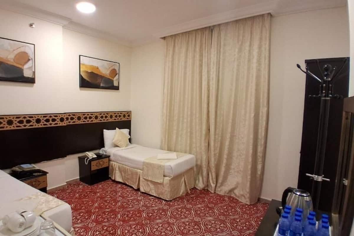 Ein Hotelzimmer mit zwei Betten, einer Minibar, einem Schreibtisch, einem Telefon und einem Fenster mit Vorhängen.