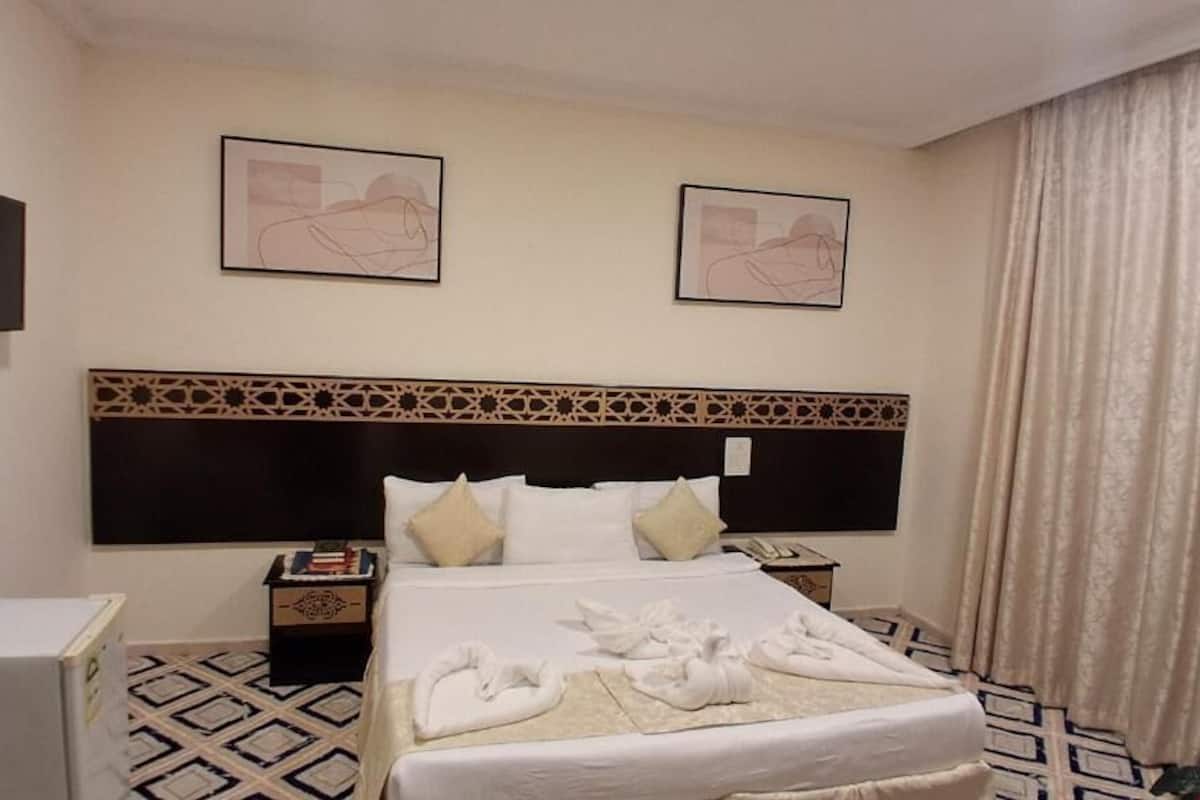 Ein Hotelzimmer mit Bett, Fernseher, Schreibtisch und Nachttisch.