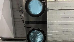 A tall, black washing machine in a room with a brick wall and a window. - Shaker Ohio contemporary home!

 (Cleveland)